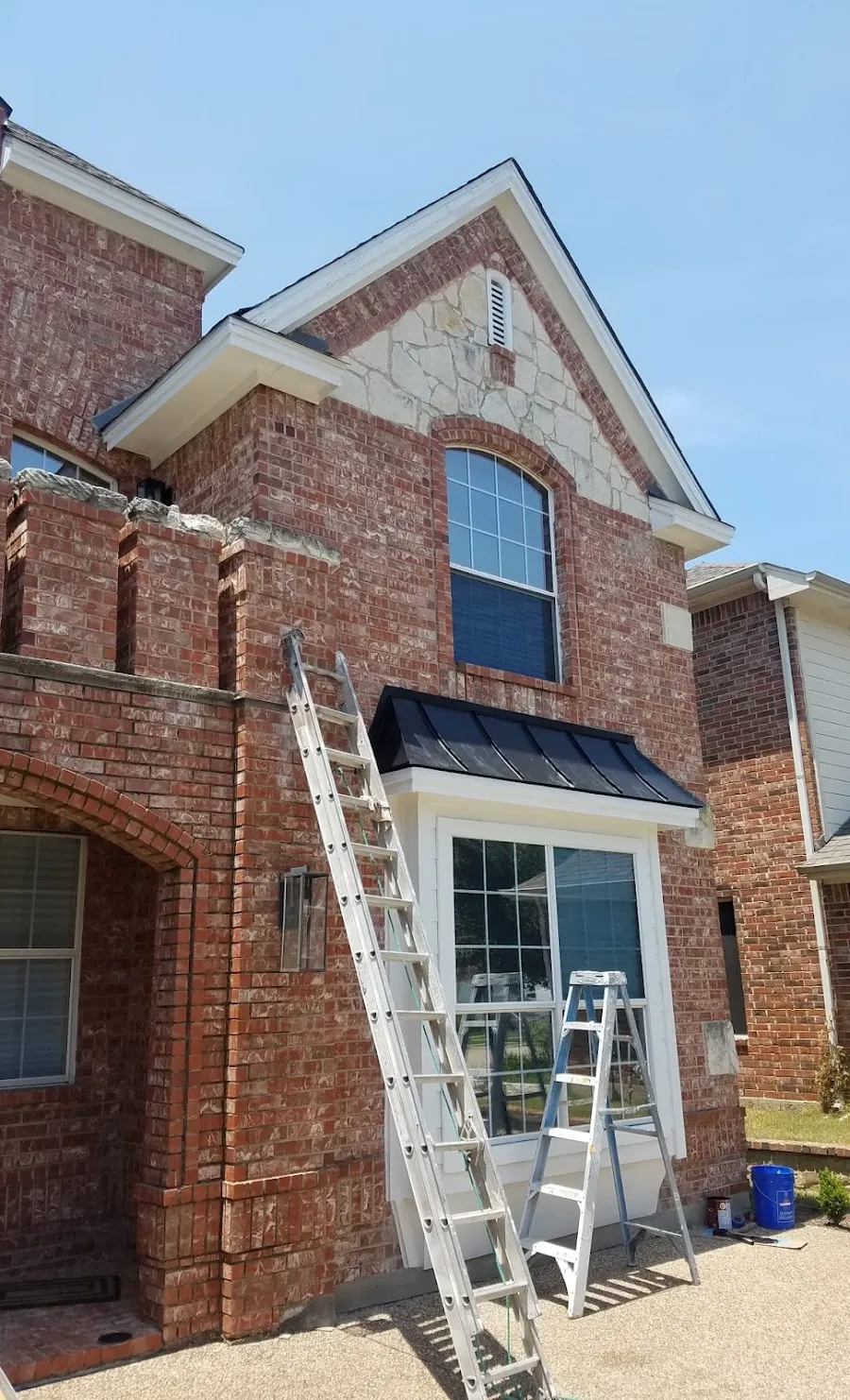 Brick two-story home with freshly painted white trim and ladders in place