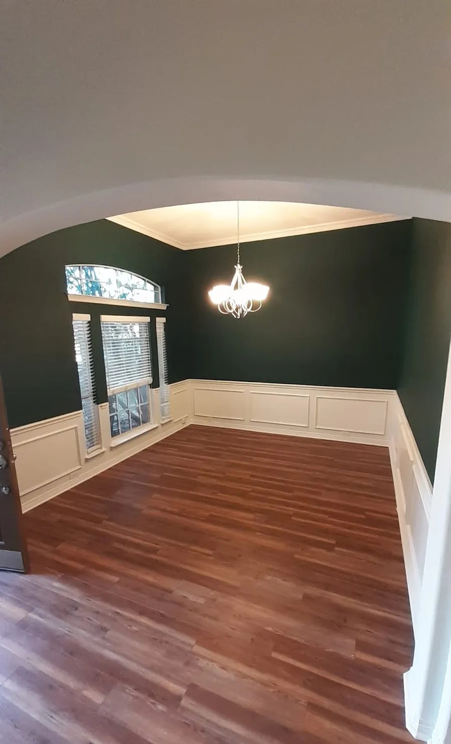 Dining room painted deep green above white wainscoting